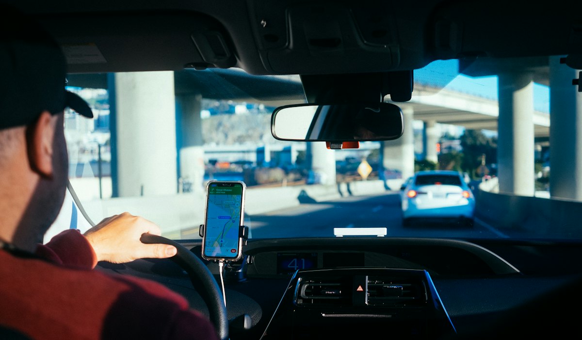 Motorista com o celular no suporte do carro, sem conseguir trabalhar pelo aplicativo